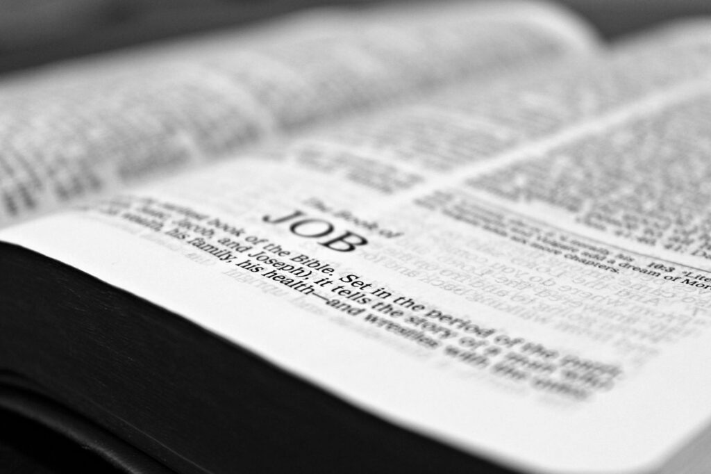 part time jobs international students uk — Close-up black and white image focusing on a Bible page with the Book of Job.